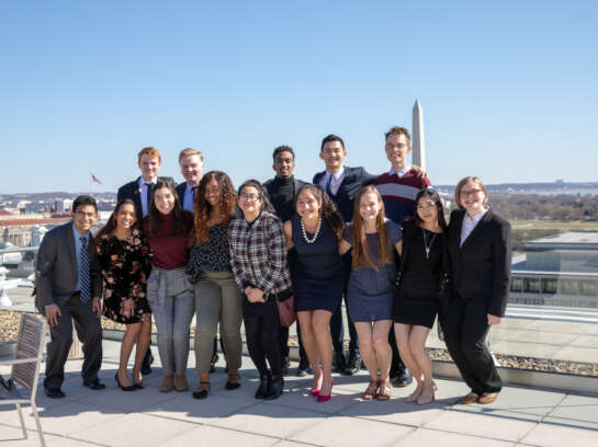 Smiling students posing for a picture with the Washington Monument in the background.