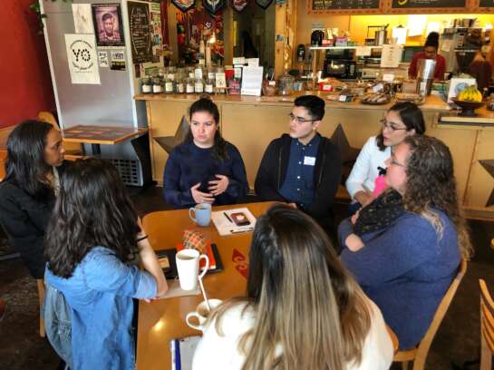 Group of students talk around table at coffee shop